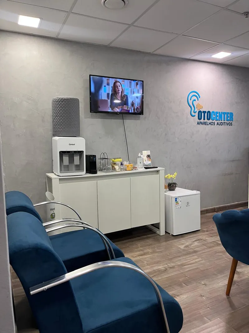 Recepção da Otocenter, com poltronas azuis e o logotipo iluminado na parede
